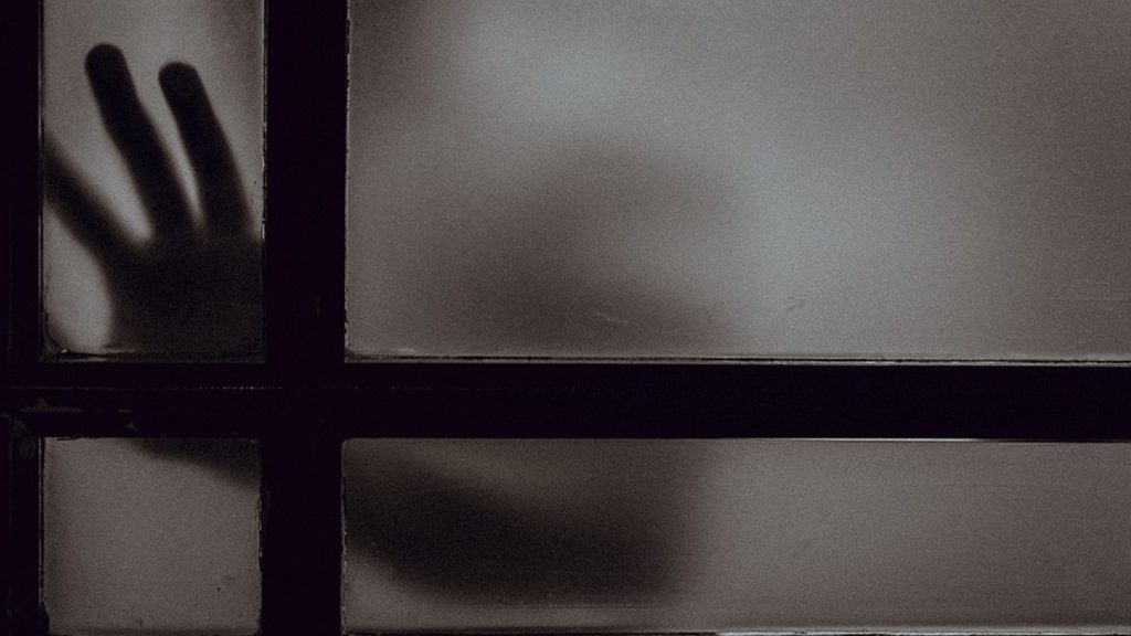 「見えない壁」を象徴する暗いカバーの向こう側から手が伸びている様子。鉄製カバーの閉塞感と、それを打破するポリカーボネート化の必要性を表現したイメージ画像。