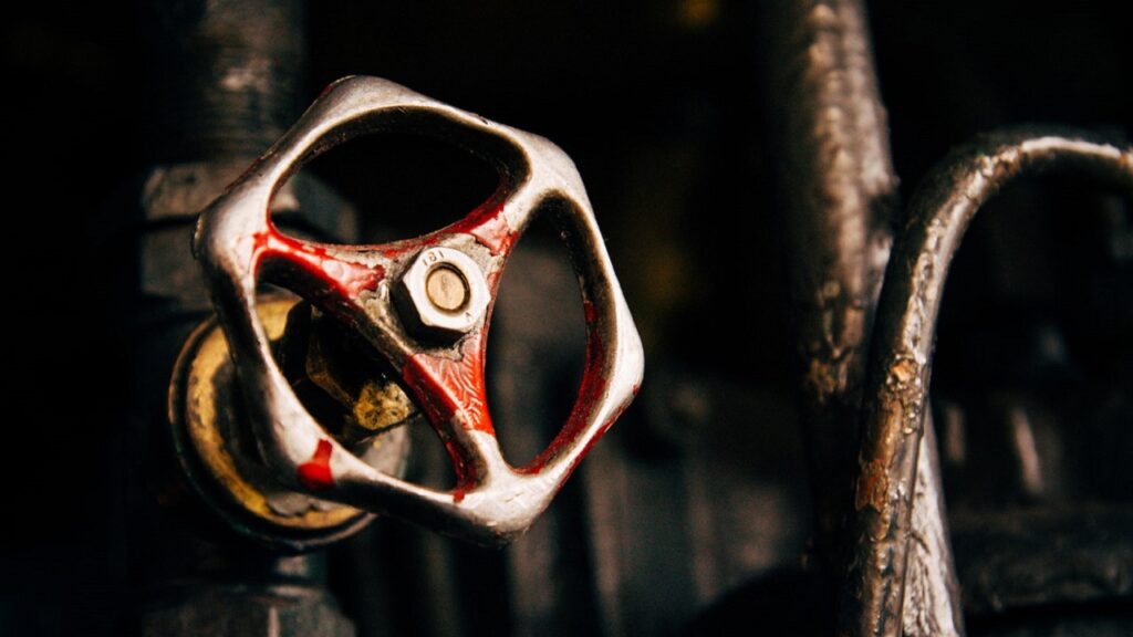 赤い塗装が剥げ、使い込まれた金属の質感が際立つ手動操作式の蒸気バルブ