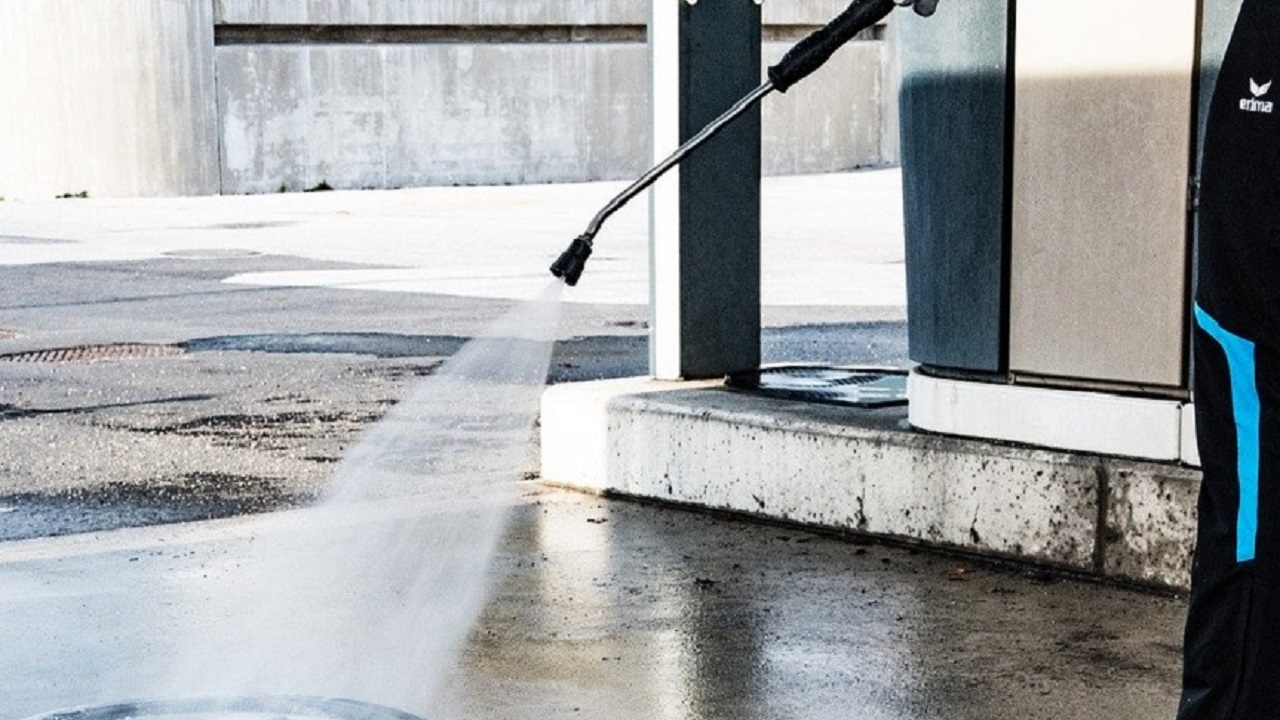 コンクリートの床を業務用高圧洗浄機で力強く洗浄している様子