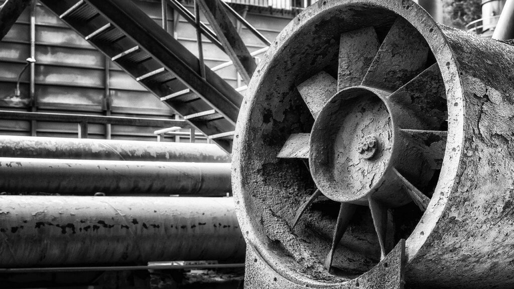 工場内に設置された、経年変化を感じさせる大型送風機のモノクロ写真。現場のリアリティを象徴する一枚。