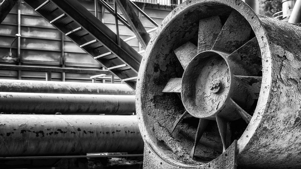 工場内に設置された、経年変化を感じさせる大型送風機のモノクロ写真。現場のリアリティを象徴する一枚。