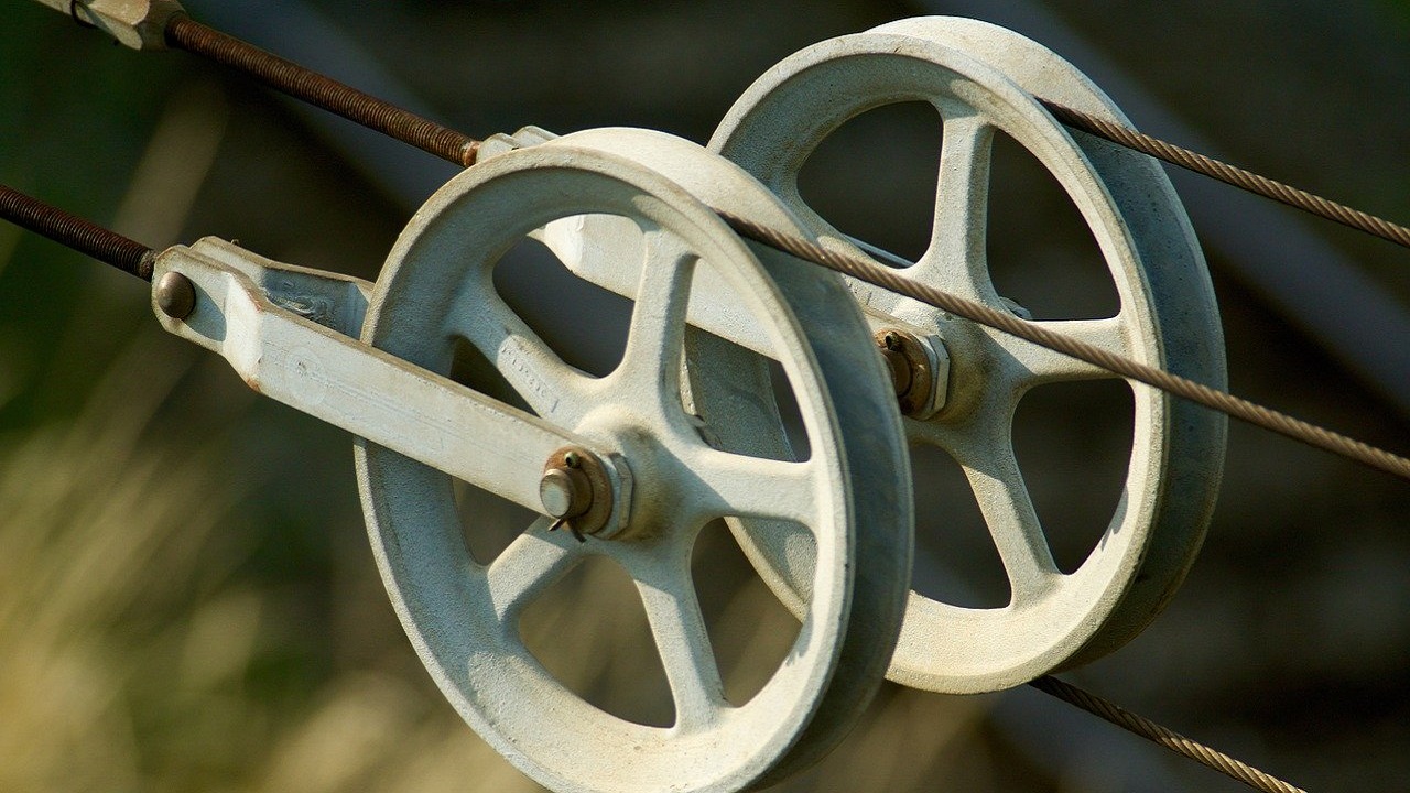 金属製ブラケットに固定された2連のプーリー。ベルトが複雑に通り、分解メンテナンスが困難そうな機械構造。